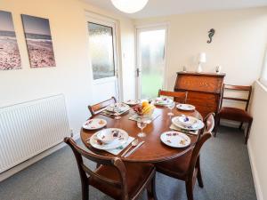 a dining room with a wooden table and chairs at Acre View in Mablethorpe