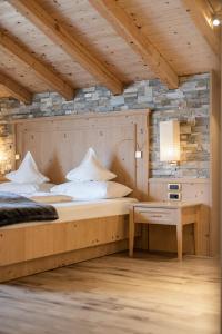 ein Schlafzimmer mit einem großen Bett und einem Schreibtisch in der Unterkunft Hotel Baumwirt in Kastelruth