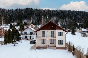 a house in the snow with trees in the background at Casa Valeria Voronet in Voronet