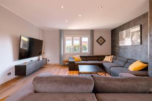 a living room with a couch and a flat screen tv at Grande maison avec piscine et jacuzzi à la campagne in Desvres