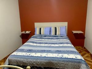 a bed with a blue and white comforter in a room at Arum Qurpawasi Hospedaje in Cabanaconde