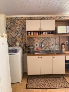 a kitchen with white cabinets and tiles on the wall at Casa da Vila in Porto Belo