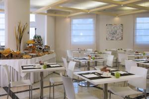 une salle à manger avec des tables et des chaises blanches dans l'établissement CDH My One Hotel Bologna, à Bologne