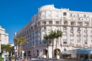 a large white building with palm trees in front of it at Palais Miramar - Suite & A18 - Vue Mer - Croisette Emplacement Unique - 20M Plage - WIFI - Clim in Cannes