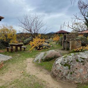un parque con banco, mesa de picnic y rocas en Casa Rural Roja, en Cebreros