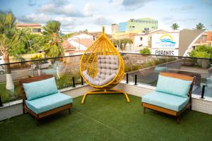 a swing sitting on top of a balcony with two chairs at Pousada Águas de Maragogi in Maragogi
