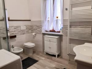 a white bathroom with a toilet and a sink at Grazioso bilocale Merlino, luminoso con vista Santuario, wifi in Giaveno