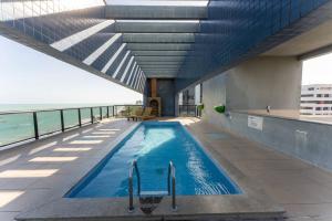een zwembad in een gebouw met uitzicht op de oceaan bij Neo B Mar PAJUÇARA 2Qts 2WIFI 2 GAR - Adm Nutells in Maceió