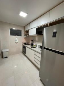 una cocina con nevera de acero inoxidable y armarios blancos en Seu lar no melhor de Recife - Boa Viagem., en Recife