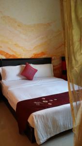 a bedroom with a large white bed with red pillows at Crescent Bay Inn in Kenting