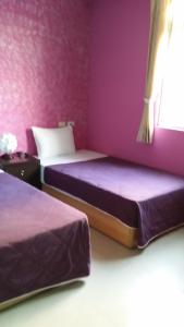 two beds in a room with purple walls at Crescent Bay Inn in Kenting