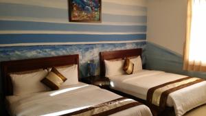 two beds in a room with blue and white stripes at Crescent Bay Inn in Kenting