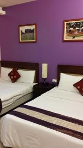 two beds in a room with a purple wall at Crescent Bay Inn in Kenting