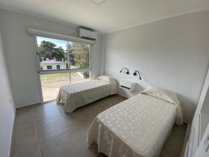 - une chambre avec 2 lits et une grande fenêtre dans l'établissement Complejo Bosque y Mar, à San Clemente del Tuyú