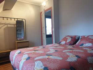 1 dormitorio con cama con colcha de flores y espejo en Le Marsouin, en Sangatte