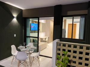 Un comedor con una mesa de cristal y sillas blancas. en Flat Espetacular em Porto de Galinhas Mana Beach Experiênce, en Porto de Galinhas