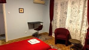 Una habitación de hotel con una cama roja y una silla. en Peti, en Belgrado