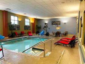 una piscina en una habitación con sillas y mesas rojas en Jefferson Street Inn, a member of Radisson Individuals, en Wausau