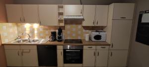 a kitchen with white cabinets and a sink and a microwave at Appartement 5 personnes à deux kilomètres des pistes in La Bresse