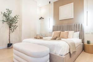 um quarto com uma grande cama branca e um repousa-pés brancos. em NEW Sophisticated apartment with balcony & city views by REMS em Málaga