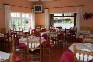 a dining room with tables and chairs and a tv at O Lar de Carmiña in Devesa