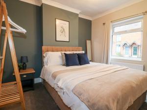 Un dormitorio con una cama con almohadas azules y una escalera en The Crooked Cottage, en Ashbourne