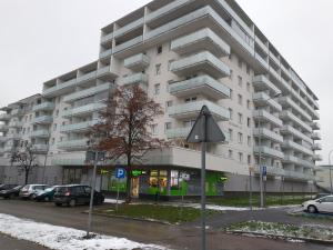 duży biały budynek z samochodami zaparkowanymi na parkingu w obiekcie AGAR HOUSE Reymonta w mieście Łomża