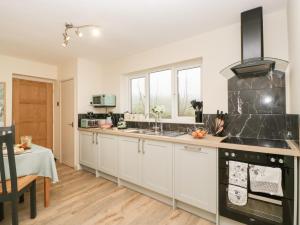 a kitchen with white cabinets and a black appliances at Palace Bungalow in Hereford