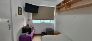 uma sala de estar com uma televisão e uma mesa roxa em Private Cozy room with batroom in Miraflores em Lima