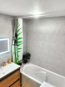 a bathroom with a white tub and a sink at Chaleureuse Maisonnette Lyon in Meyzieu