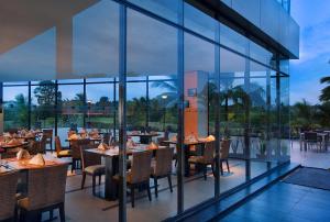 restauracja ze stołami, krzesłami i oknami w obiekcie Novotel Manado Golf Resort & Convention Center w mieście Manado