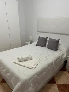 ein weißes Bett mit einem Handtuch darüber in der Unterkunft El Torreón 3 in Lora del Río