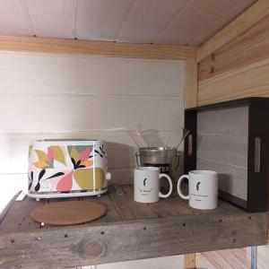 a counter with three coffee mugs and a microwave at Tiny & spa La Libellule en Périgord in La Force