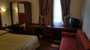 シラクーサにあるAretusa Palace Hotelのベッド、デスク、テレビが備わるホテルルームです。