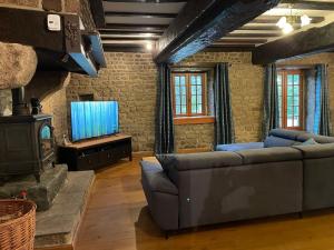 un soggiorno con un divano e una televisione di MAISON LA BURELIERE - holiday home for families, groups, couples a Gorron