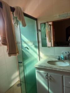 a bathroom with a glass shower and a sink at Casa pé na areia (50 mestros da praia) in Peruíbe