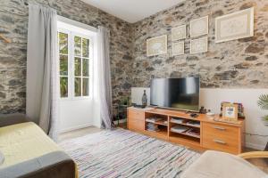 ein Wohnzimmer mit einem TV an einer Steinmauer in der Unterkunft Casa D`Avó Celina in Funchal