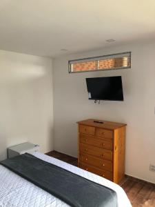 een slaapkamer met een bed, een tv en een dressoir bij Pousada Litorânea in Saquarema