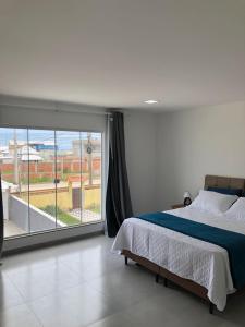 a bedroom with a bed and a large window at Pousada Litorânea in Saquarema