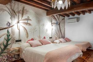 two beds in a room with a mural of palm trees at Apartamentos La Solana de Monfragüe in Malpartida de Plasencia