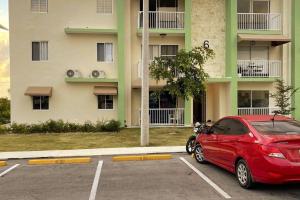 un coche rojo estacionado en un estacionamiento frente a un edificio en Nice apartment in punca cana near the airport and beaches, en Punta Cana