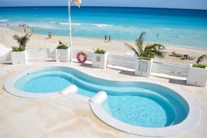 a pool on the beach with a beach in the background at Estudio 1A sobre hermosa playa, excelente opción in Cancún
