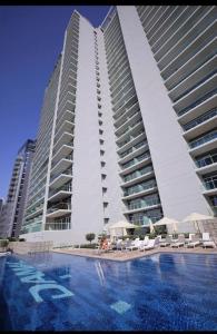 two tall buildings with umbrellas in front of a swimming pool at New Luxury Modern Canal View. in Dubai