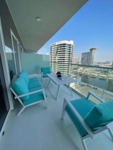 New Luxury Modern Canal View. في دبي: شرفة مع كراسي زرقاء وطاولة على مبنى