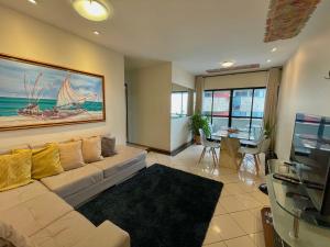 een woonkamer met een bank en een schilderij van een boot bij BEIRA MAR 2 Quartos com Ar e Cozinha Completa in Maceió