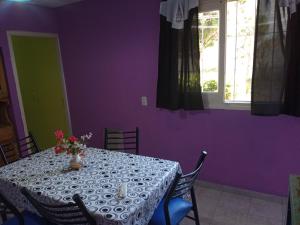 Una mesa con un jarrón de flores y una ventana. en Casa tres ambientes con jardín y estacionamiento, en Mar de Ajó