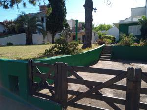 una puerta de madera frente a una valla verde en Casa tres ambientes con jardín y estacionamiento en Mar de Ajó