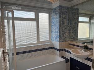 a bathroom with a tub and a sink at TJ Homes - One double bed room with garden view - Next to tube station in Ruislip