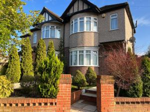 une maison avec une clôture en briques devant elle dans l'établissement TJ Homes - One double bed room with garden view - Next to tube station, à Ruislip