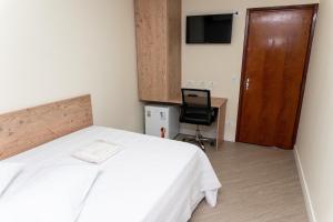 Dormitorio con cama, escritorio y TV en Hotel Descalvado, en Descalvado